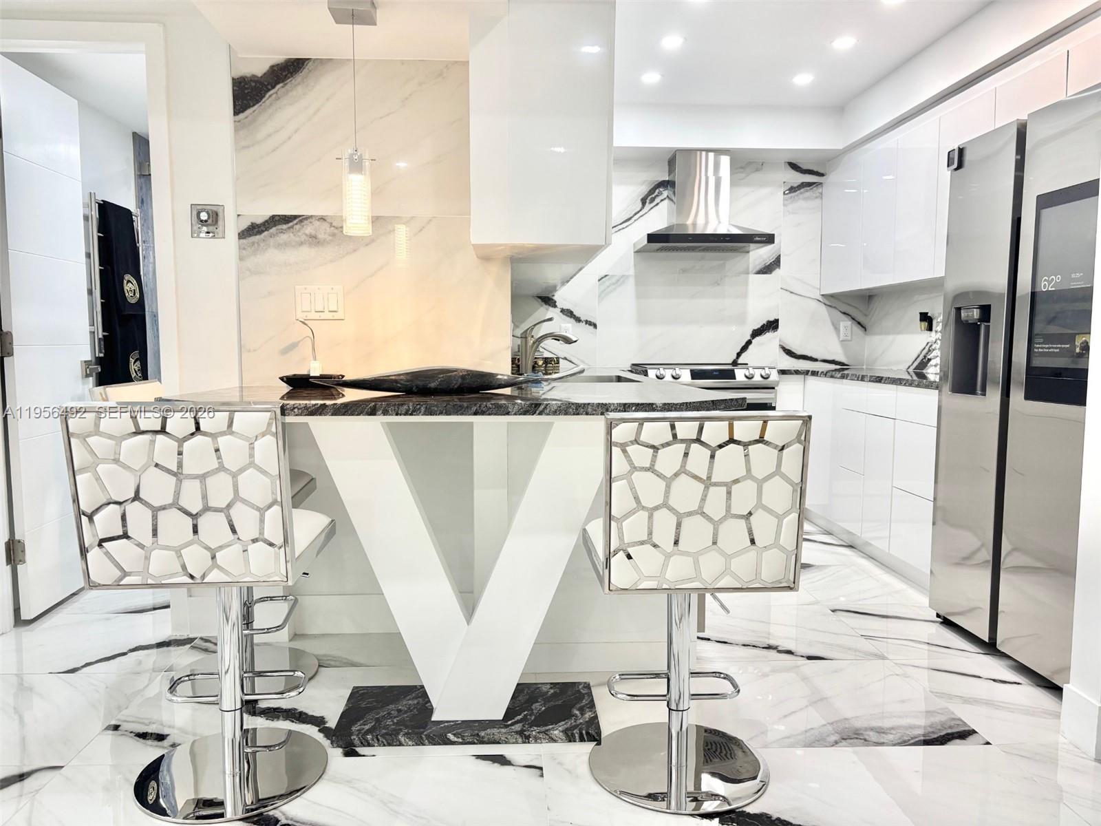 A modern kitchen features white cabinets, marble-patterned surfaces, and two geometric-patterned bar stools — 1965 S Ocean Dr # 15B, Hallandale Beach FL 33009, HALLANDALE BEACH, FL