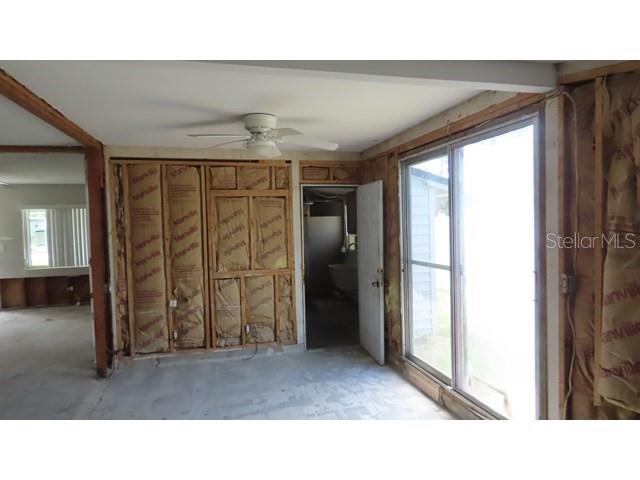 An unfinished room features exposed wall studs, fiberglass insulation, a ceiling fan, and sliding doors — 6060 62ND STREET N, ST PETERSBURG, FL