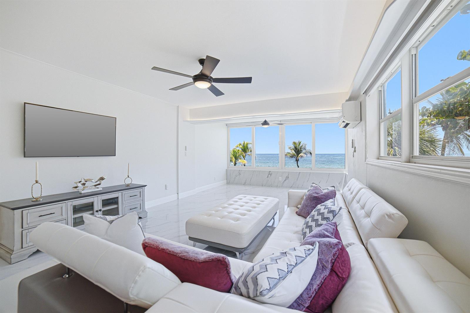 A bright living room features white marble floors, a large sectional sofa, and ocean views — 8 Briny Avenue # 206, Pompano Beach FL 33062, POMPANO BEACH, FL