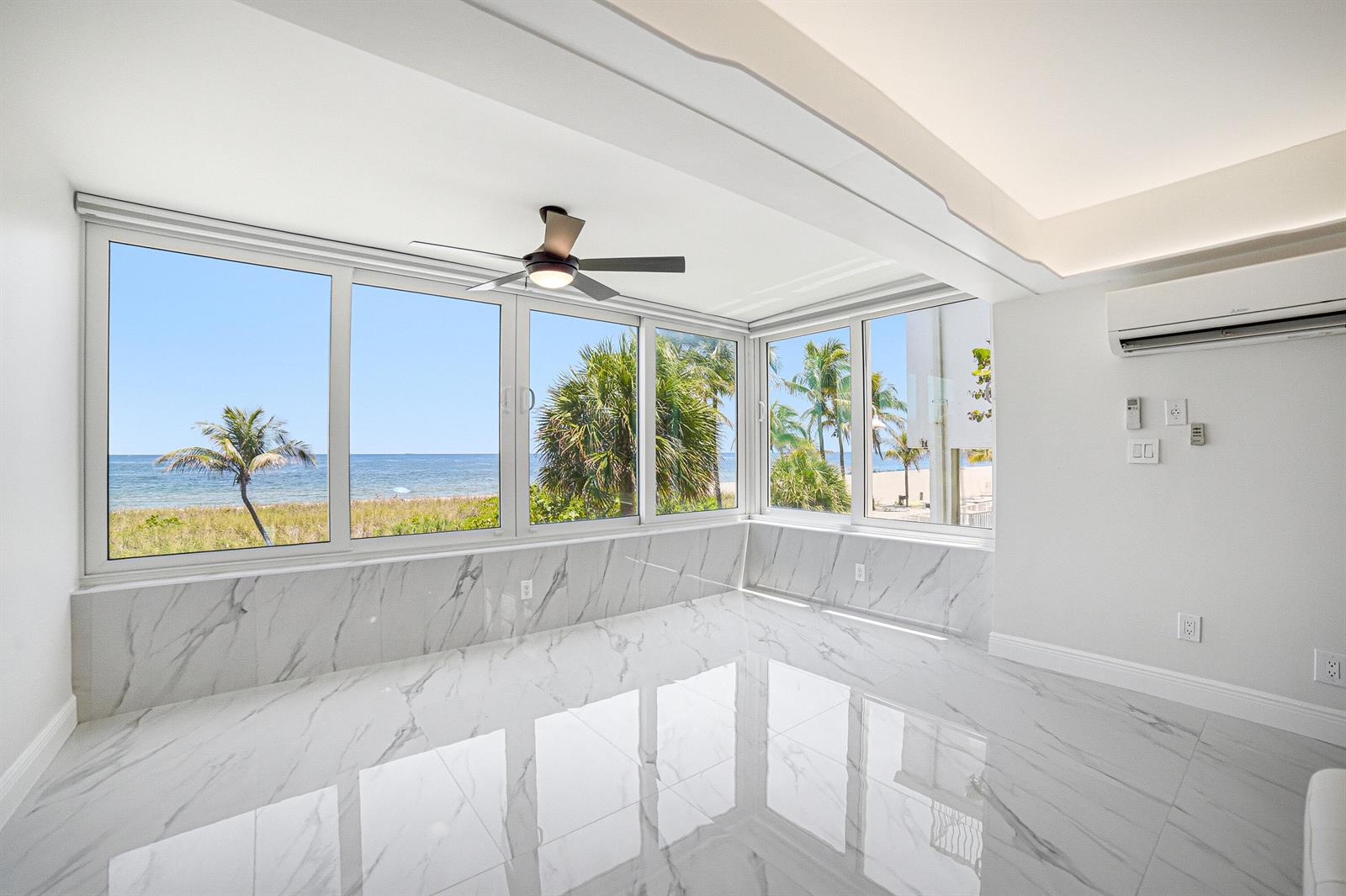 A bright room with white marble floors, wall paneling, and large windows overlooking the ocean — 8 Briny Avenue # 206, Pompano Beach FL 33062, POMPANO BEACH, FL