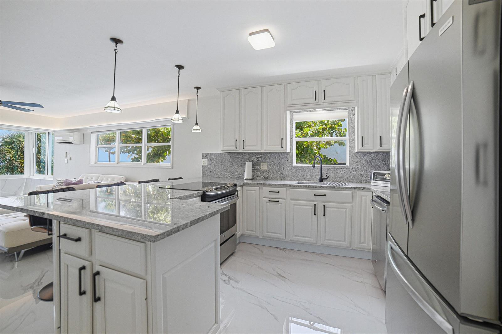 A white kitchen features granite countertops, stainless steel appliances, and a large center island — 8 Briny Avenue # 206, Pompano Beach FL 33062, POMPANO BEACH, FL