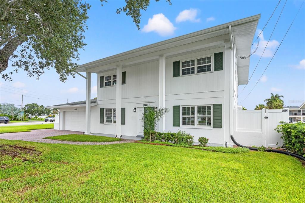 A two-story white house with green shutters, a garage, and a front lawn — 4000 14TH WAY NE, ST PETERSBURG, FL
