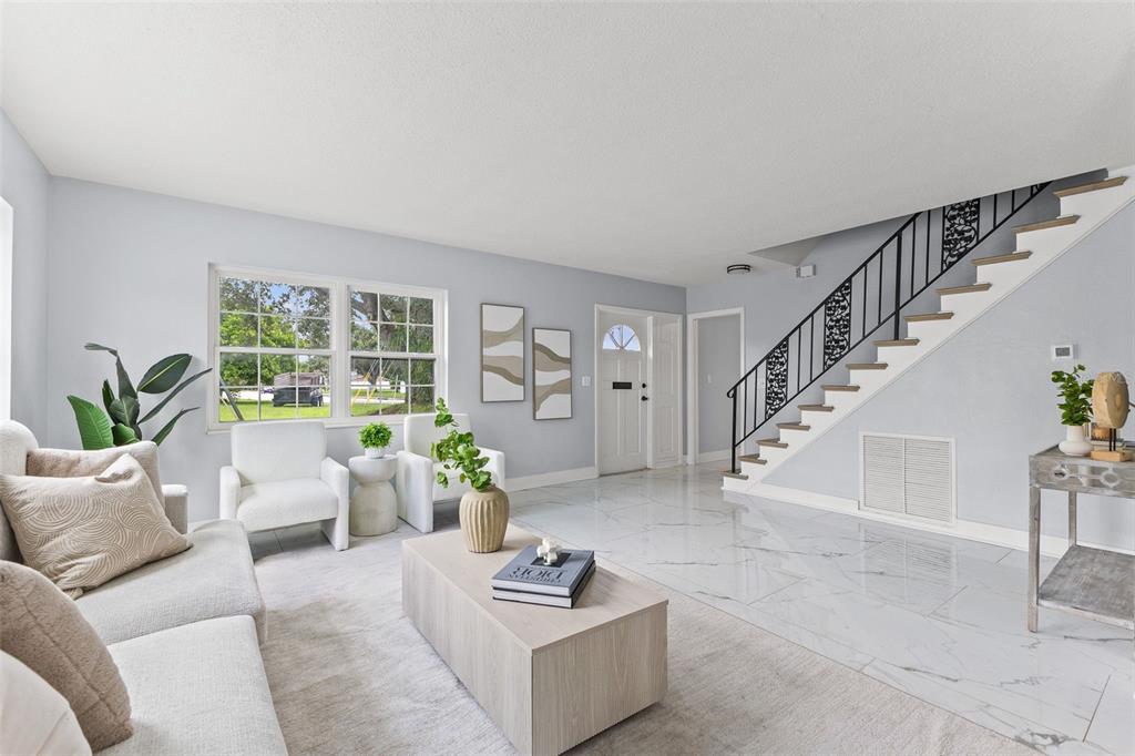 A living room features white marble floors, a staircase with black railings, and neutral furniture — 4000 14TH WAY NE, ST PETERSBURG, FL
