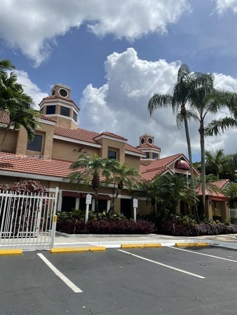 A tan commercial building with a red tile roof and palm trees under a cloudy sky — 10500 SW 155th Ct # 10112, Miami FL 33196, MIAMI, FL
