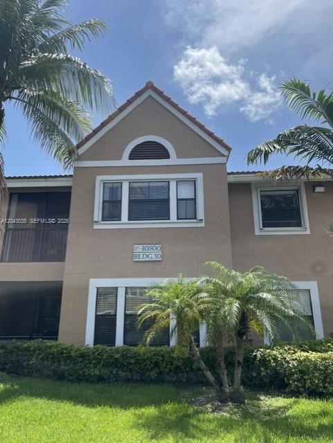 The exterior of a tan two-story building features a peaked roof and palm trees — 10500 SW 155th Ct # 10112, Miami FL 33196, MIAMI, FL