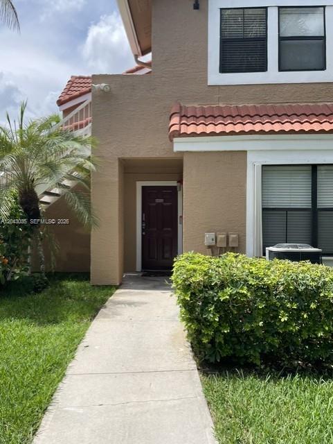 A concrete walkway leads to the dark brown front door of a tan stucco townhouse — 10500 SW 155th Ct # 10112, Miami FL 33196, MIAMI, FL