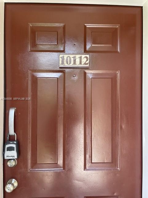 A brown front door features a silver lockbox hanging from the handle and a number plaque — 10500 SW 155th Ct # 10112, Miami FL 33196, MIAMI, FL