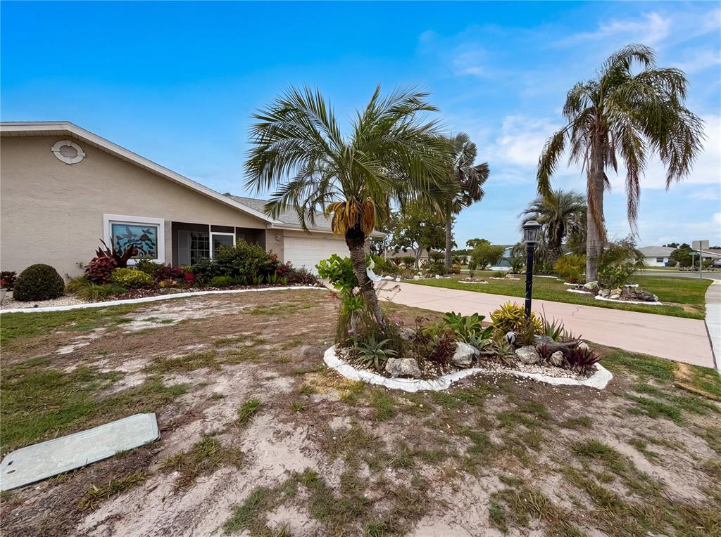 A single-story house with a palm tree and landscaped garden in the front yard — 1838 N PEBBLE BEACH BOULEVARD, SUN CITY CENTER, FL