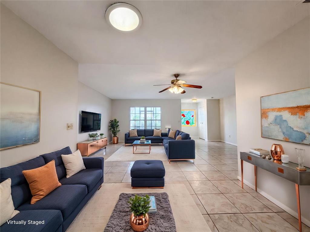 A living room features two blue sectionals, tile flooring, and a ceiling fan — 1838 N PEBBLE BEACH BOULEVARD, SUN CITY CENTER, FL