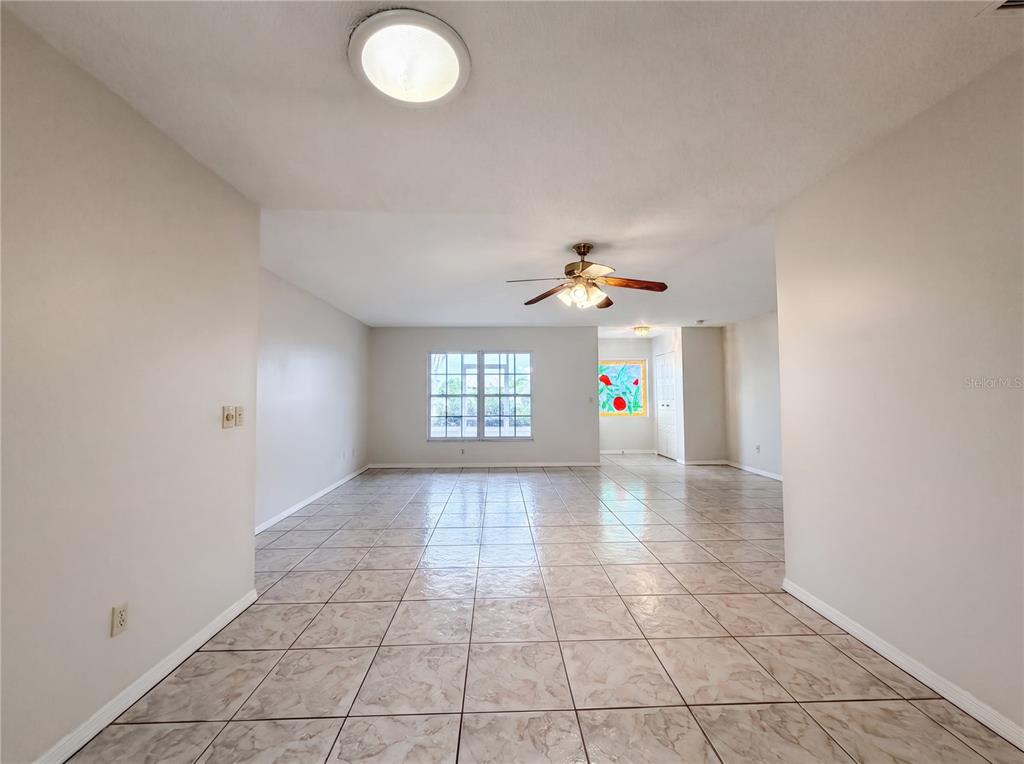 A spacious room with light-colored walls, tiled flooring, a ceiling fan, and a large window — 1838 N PEBBLE BEACH BOULEVARD, SUN CITY CENTER, FL