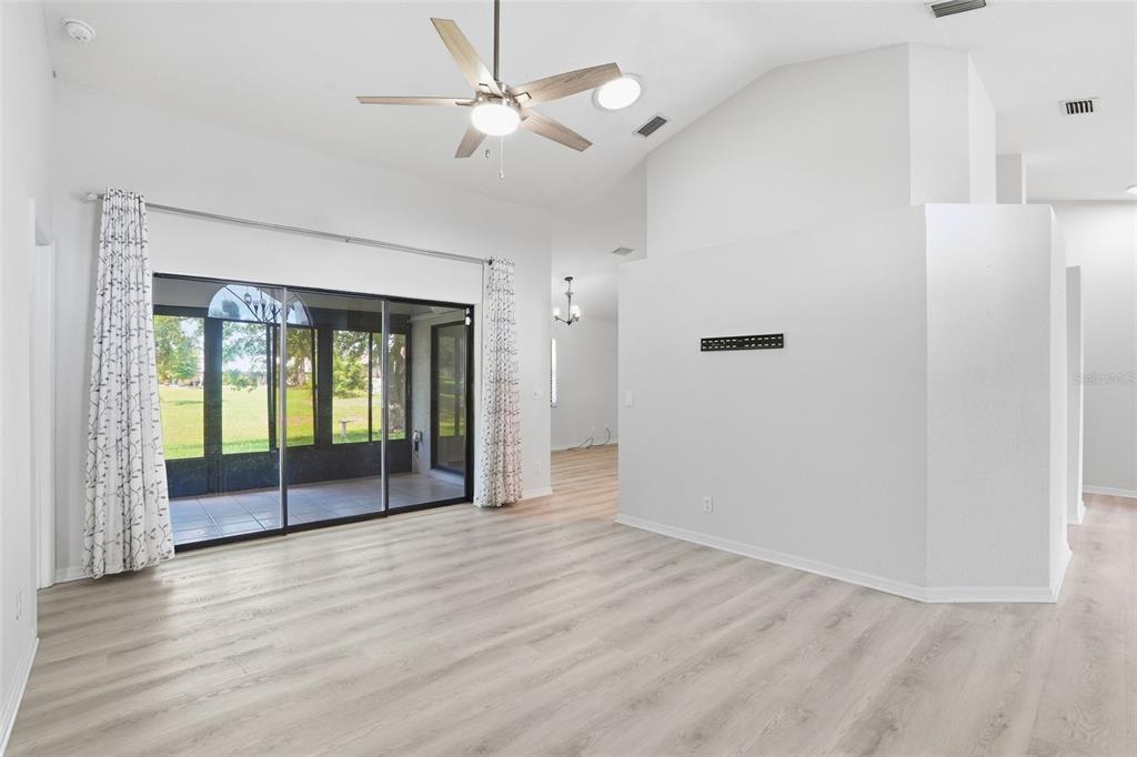 A modern living room features white walls, a vaulted ceiling, and blue accent furniture — 26070 DOLMAN COURT, PUNTA GORDA, FL