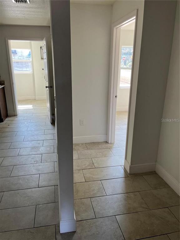 A hallway with light-colored tile flooring leads to two doorways showing interior rooms — 3301 E IDA STREET, TAMPA, FL