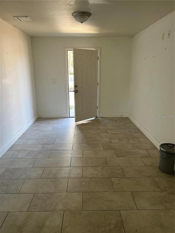 An empty room features light-colored tile flooring, white walls, and an open exterior door — 3301 E IDA STREET, TAMPA, FL