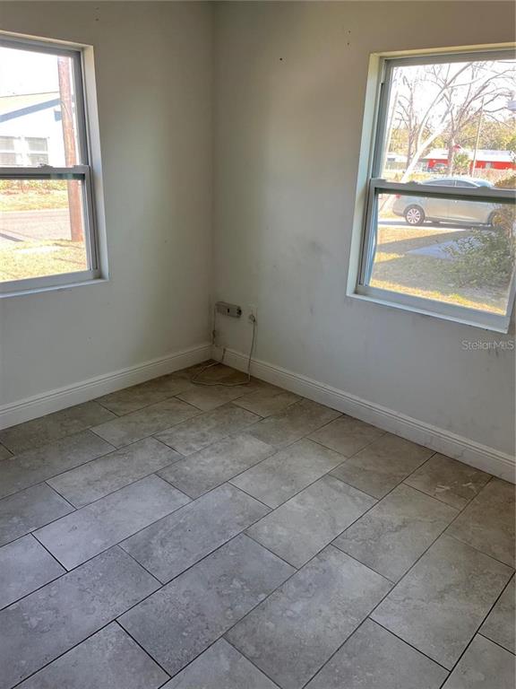 A corner room features two windows, light-colored walls, and large gray rectangular floor tiles — 3301 E IDA STREET, TAMPA, FL