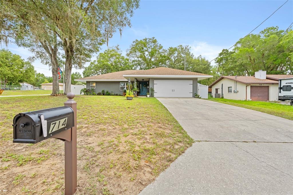 A single-story house with a gray exterior, a two-car garage, and a front lawn — 714 SPRUCE STREET, INVERNESS, FL