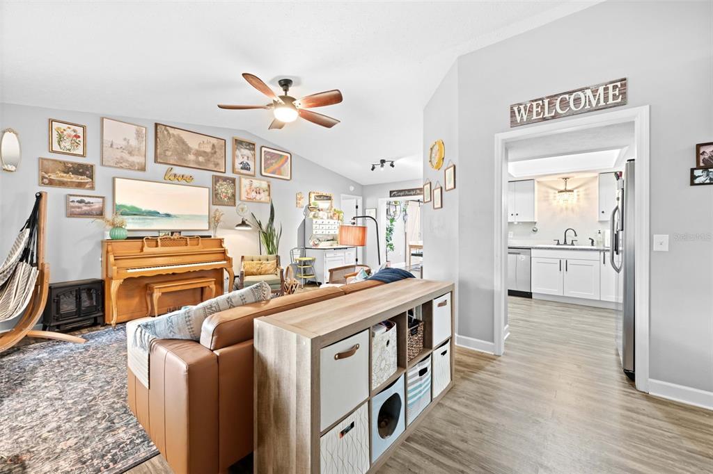A living room with a piano and sofa faces a doorway leading to a kitchen — 714 SPRUCE STREET, INVERNESS, FL