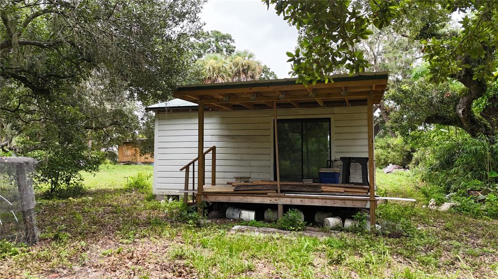 A small, weathered white cabin features a wooden deck with an unfinished roof overhang — 5404 18TH STREET BOULEVARD E, BRADENTON, FL
