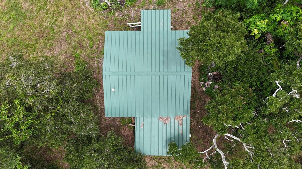 An aerial view shows a house with a green metal roof surrounded by dense trees — 5404 18TH STREET BOULEVARD E, BRADENTON, FL