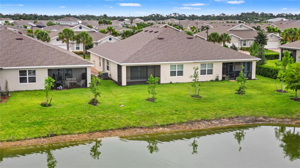 An aerial view of the rear of two suburban houses with screened lanais facing a pond — 16112 BRIDLE RIDGE STREET, PORT CHARLOTTE, FL
