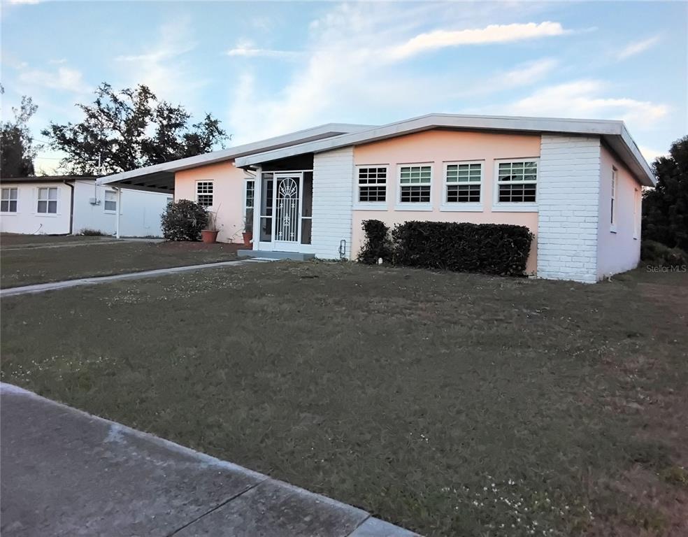 A single-story house with a peach-colored exterior, white brick accents, and a front porch — 2440 ELKCAM BOULEVARD, PORT CHARLOTTE, FL