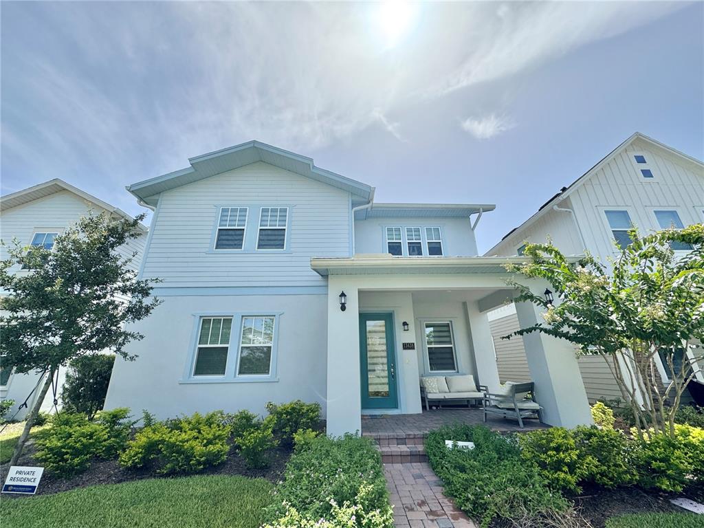 A two-story light blue house with a covered front porch and a teal front door — 13438 LEGGETT ALLEY, ORLANDO, FL
