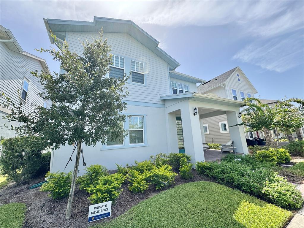 A two-story light blue house features a covered front porch and a landscaped front yard — 13438 LEGGETT ALLEY, ORLANDO, FL
