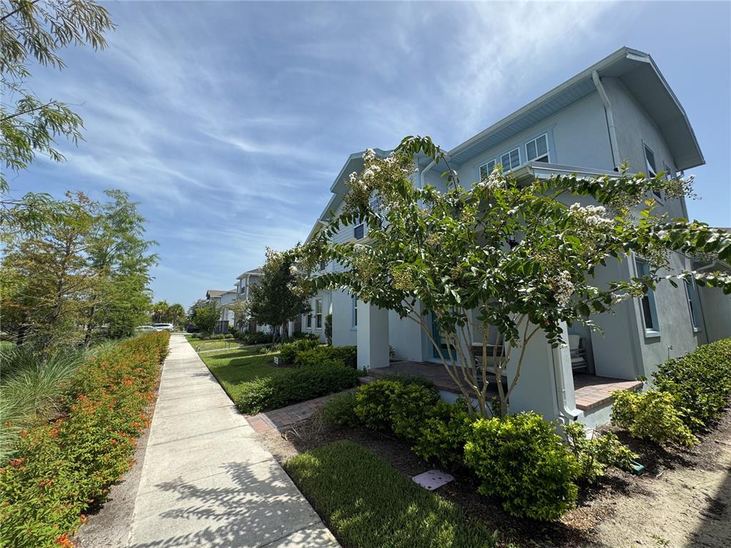 A light blue two-story house with a front porch and landscaping along a sidewalk — 13438 LEGGETT ALLEY, ORLANDO, FL