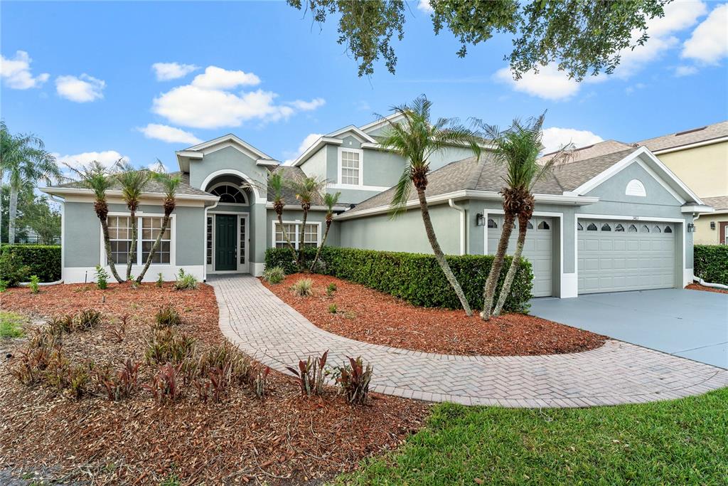 A two-story house with a gray exterior, a brick walkway, and a three-car garage — 3463 FOREST RIDGE LANE, KISSIMMEE, FL