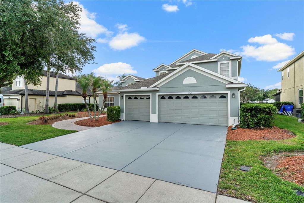 A two-story house with a gray exterior, a three-car garage, and a paved driveway — 3463 FOREST RIDGE LANE, KISSIMMEE, FL
