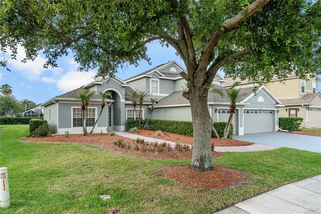 A two-story house with a gray exterior, a multi-car garage, and a large front tree — 3463 FOREST RIDGE LANE, KISSIMMEE, FL