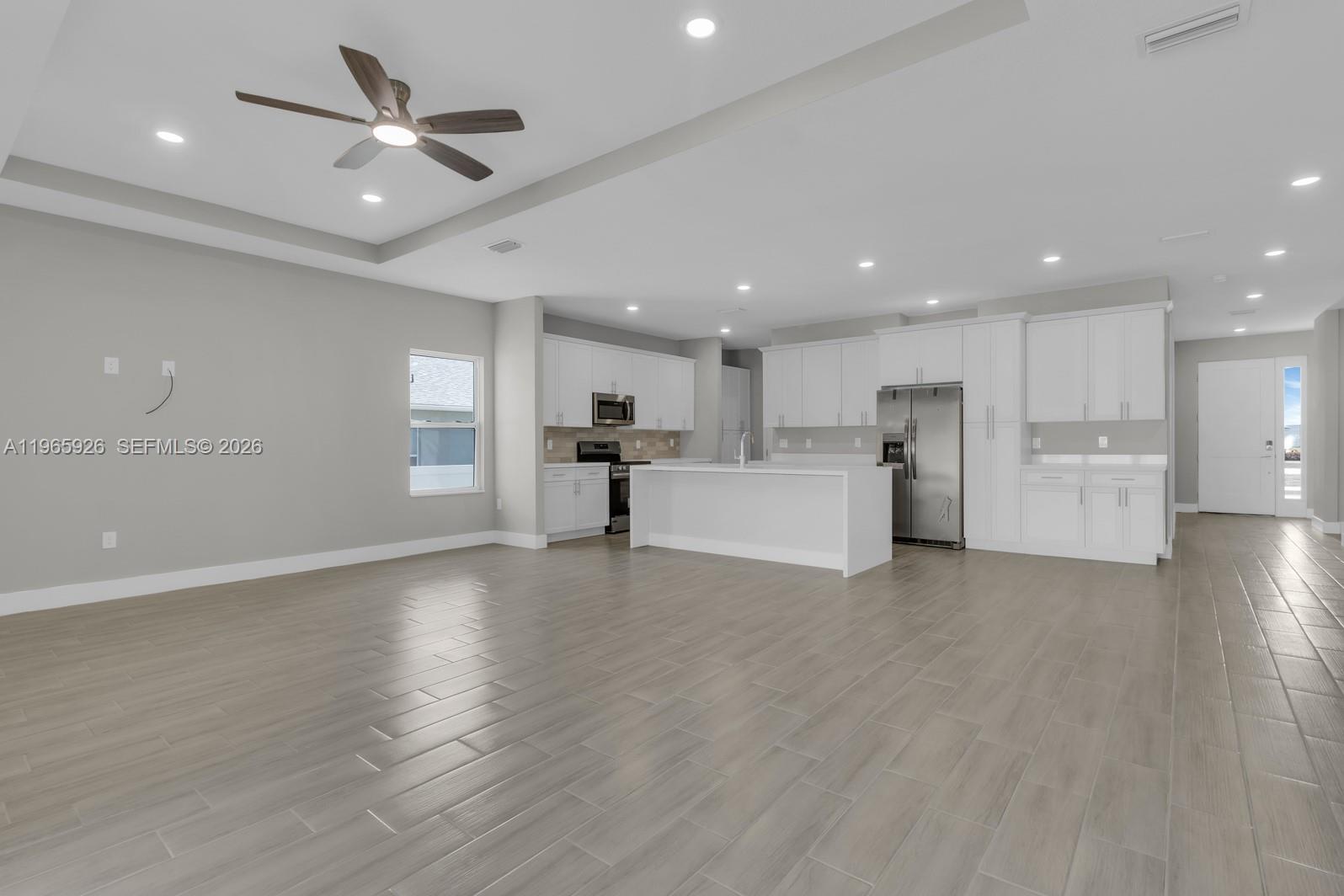 A modern open-concept kitchen features white cabinetry, a central island, and light wood-look flooring — 1811 MISSOURI, Palm Bay FL 32907, PALM BAY, FL