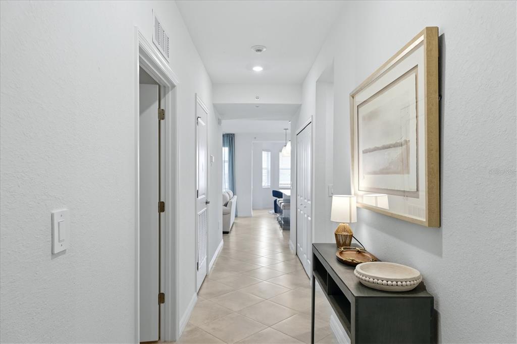 A hallway with tile flooring leads to an open living area with a console table — 19140 SCALLOP LOOP UNIT 102, LAKEWOOD RANCH, FL