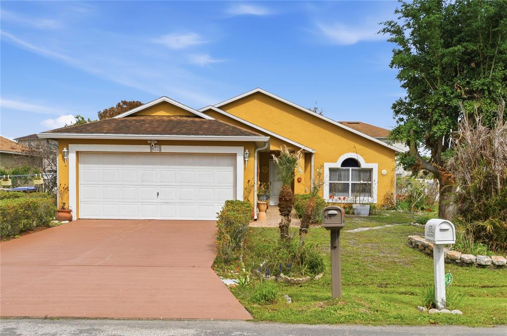 A yellow single-story house with a white garage door and a red concrete driveway — 675 BASINGSTOKE COURT, POINCIANA, FL