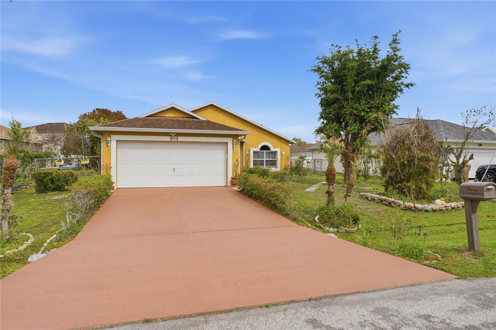 A yellow single-story house with a two-car garage and a paved driveway — 675 BASINGSTOKE COURT, POINCIANA, FL