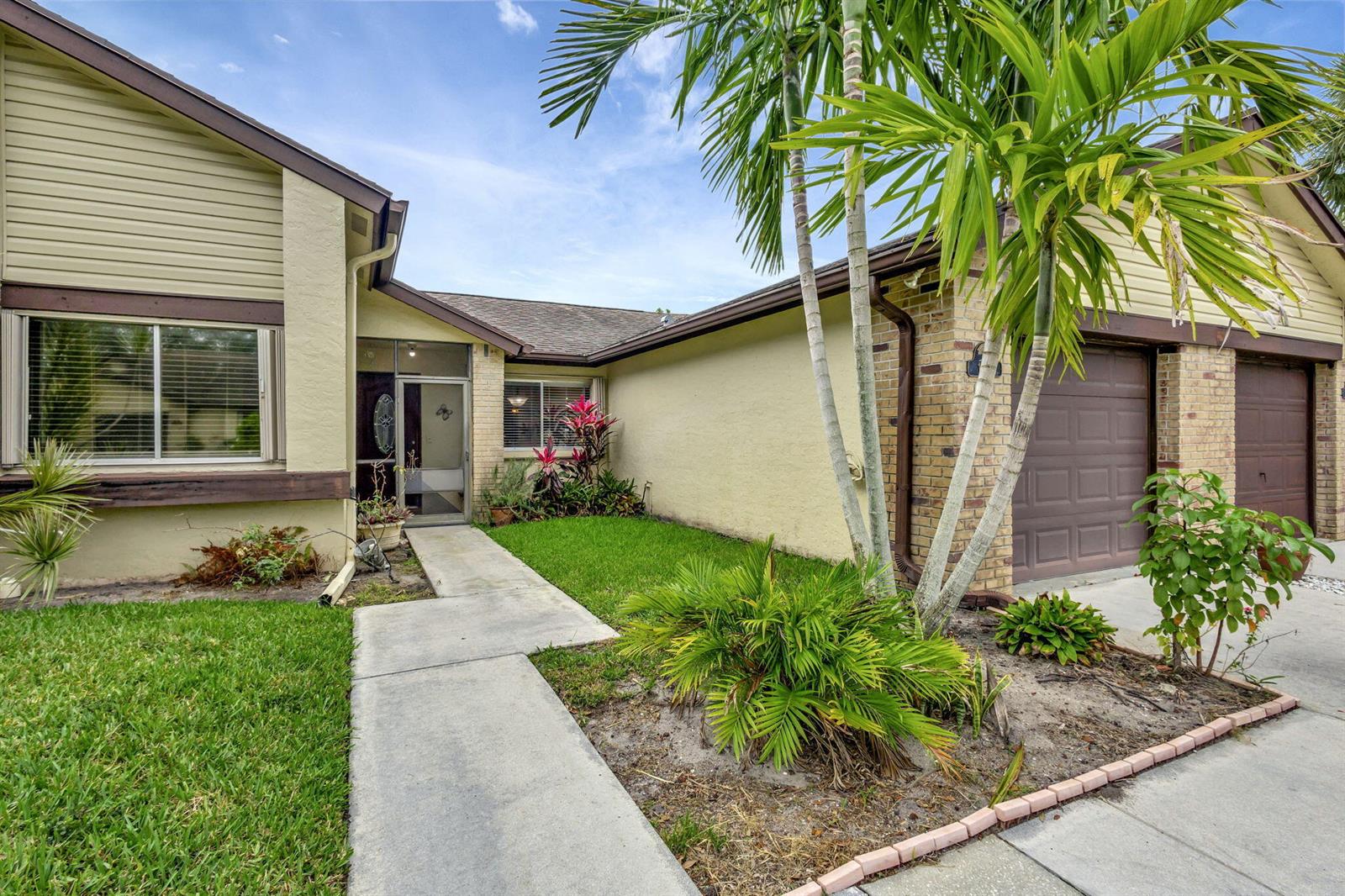 A single-story house with tan siding, brick accents, a two-car garage, and a front walkway — 178 Ramblewood Circle, Royal Palm Beach FL 33411, ROYAL PALM BEACH, FL