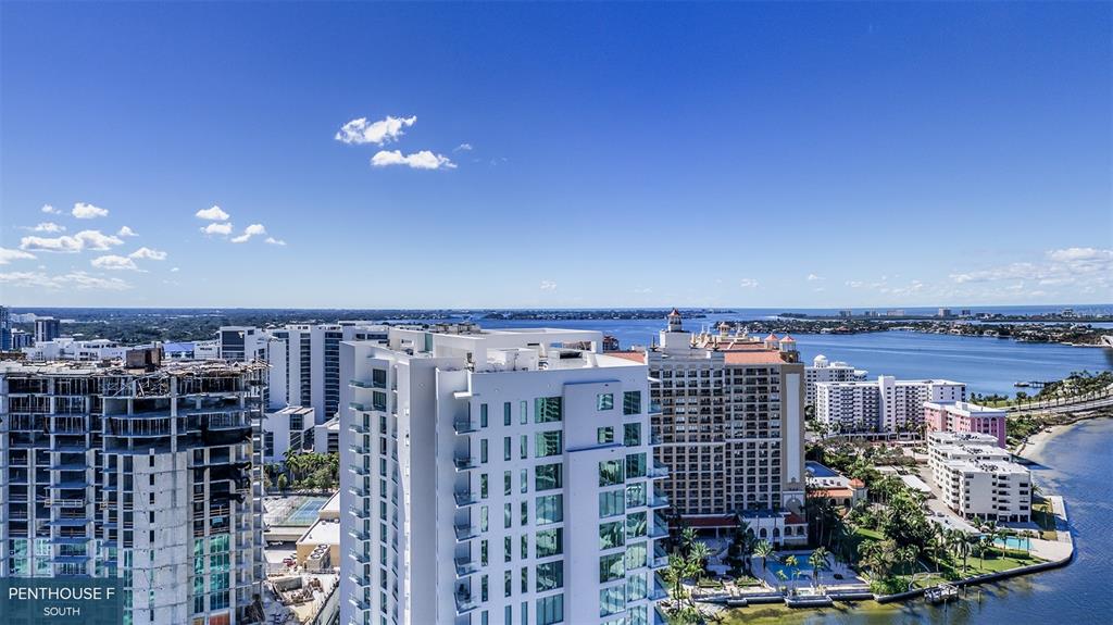 An aerial view shows high-rise buildings, a construction site, and a waterfront area under a blue sky — 555 QUAY COMMON UNIT 2001, SARASOTA, FL