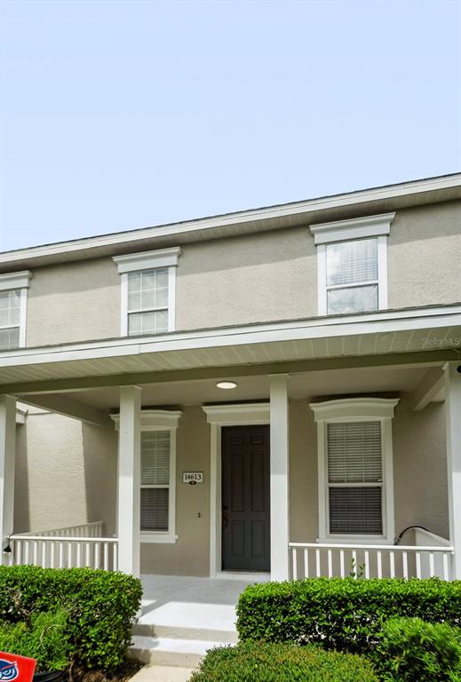 A two-story house exterior features a covered front porch, a dark door, and beige siding — 14613 CLARKSON DRIVE, ORLANDO, FL