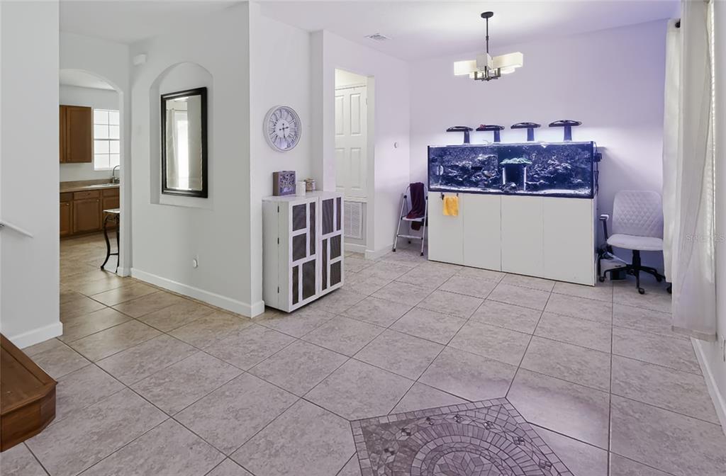 A tiled dining area features a large aquarium, a white storage cabinet, and a chandelier — 14613 CLARKSON DRIVE, ORLANDO, FL