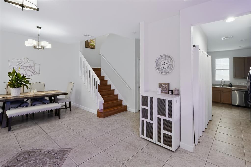 A dining area with a wooden staircase and a view into a kitchen — 14613 CLARKSON DRIVE, ORLANDO, FL