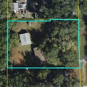 This is an aerial view of a property lot outlined in blue with two buildings — 136 S COMMERCIAL STREET, COLEMAN, FL