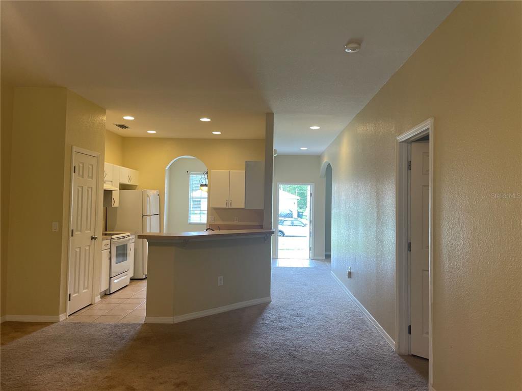A kitchen with white cabinets and a breakfast bar overlooks a carpeted living area — 1818 GOVERNOR AVENUE, NORTH PORT, FL