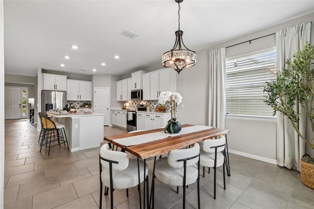 A dining area with a live-edge wooden table sits adjacent to a white kitchen — 7629 BROAD RIVER AVENUE, LAND O LAKES, FL
