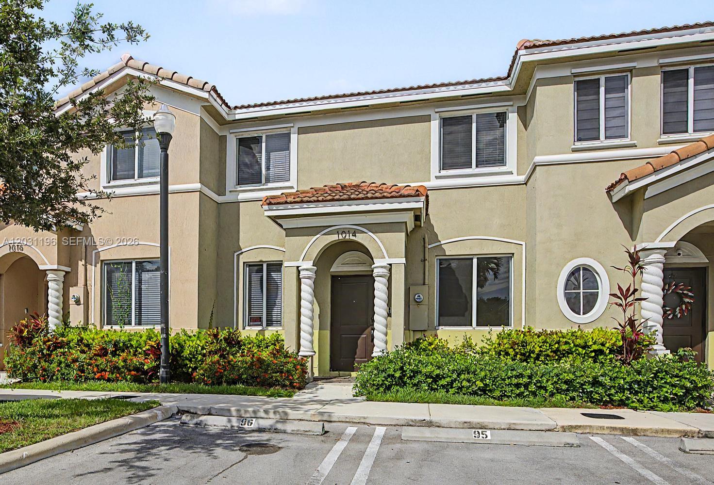 A two-story townhouse exterior features a covered entryway with spiral columns and a tiled roof — 1014 SE 23rd Ave, Homestead FL 33035, HOMESTEAD, FL