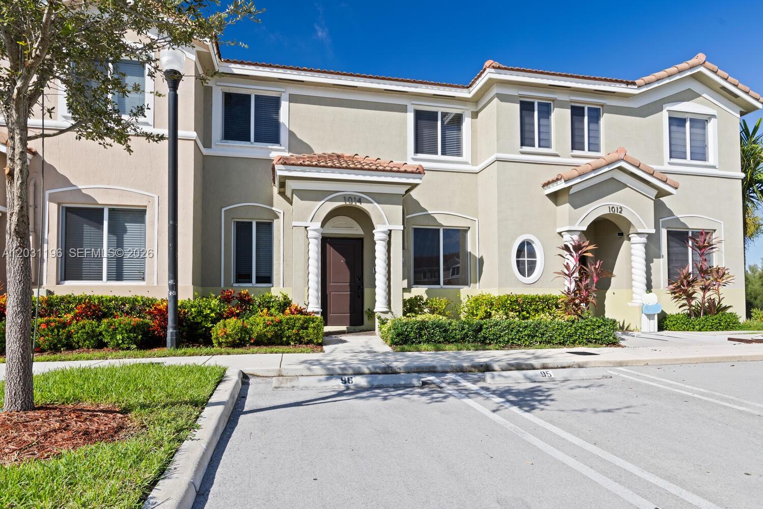 A two-story townhouse exterior features beige stucco walls, tiled roof sections, and two front entrances — 1014 SE 23rd Ave, Homestead FL 33035, HOMESTEAD, FL