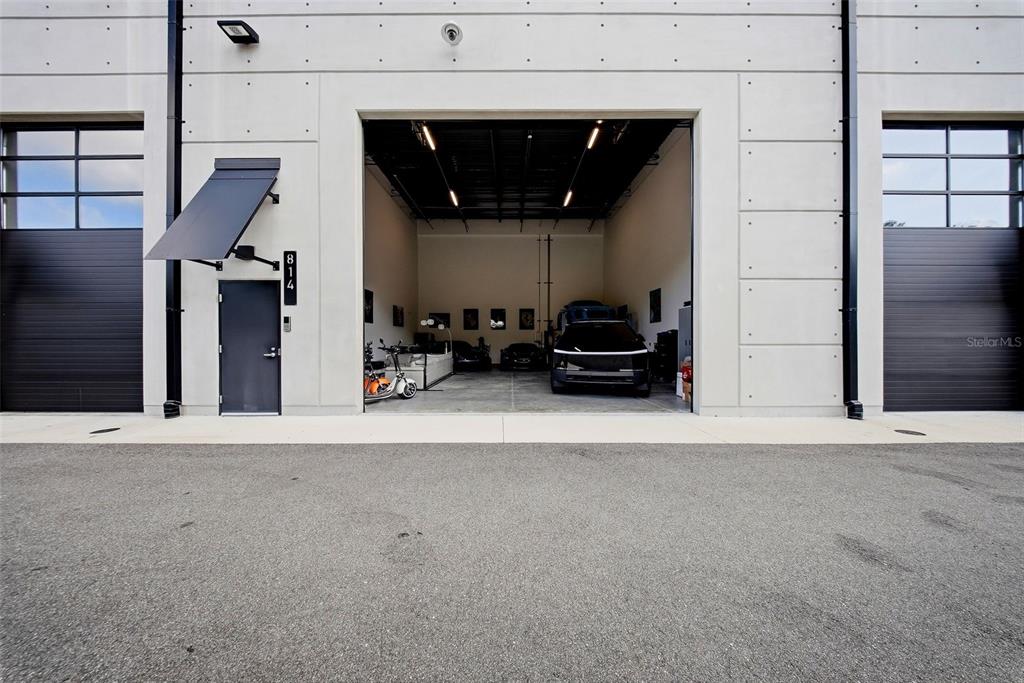 An exterior view shows a concrete building with a central open garage bay and two side doors — 6500 MOTOR ENCLAVE WAY UNIT 814, TAMPA, FL