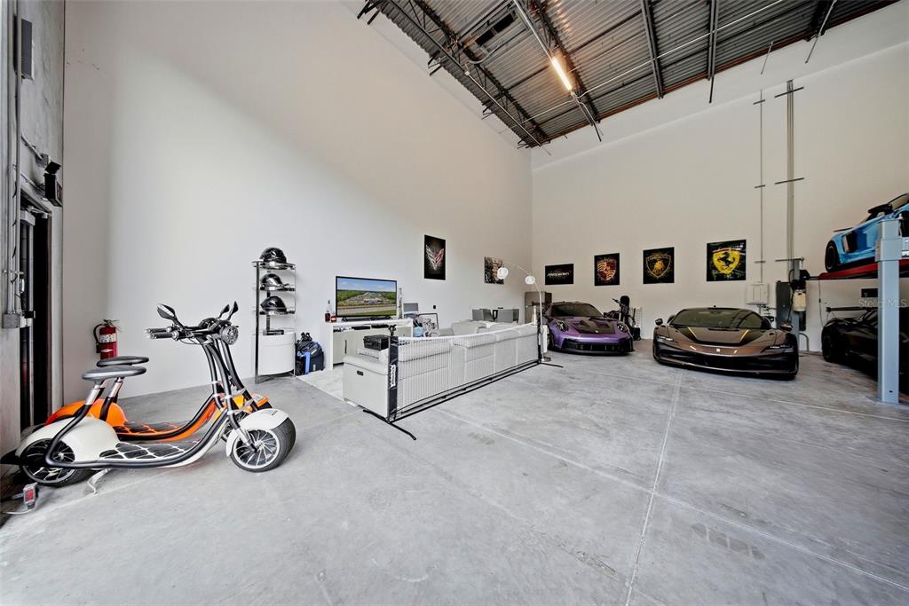 A spacious garage featuring a lounge area, a scooter, and several luxury sports cars — 6500 MOTOR ENCLAVE WAY UNIT 814, TAMPA, FL