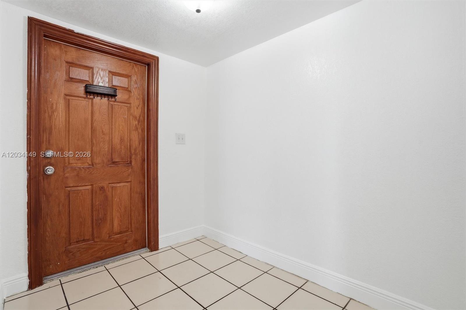 An interior view shows a wooden door with a mail slot and tiled flooring — 1389 NW 31st Ave # B, Miami FL 33125, MIAMI, FL