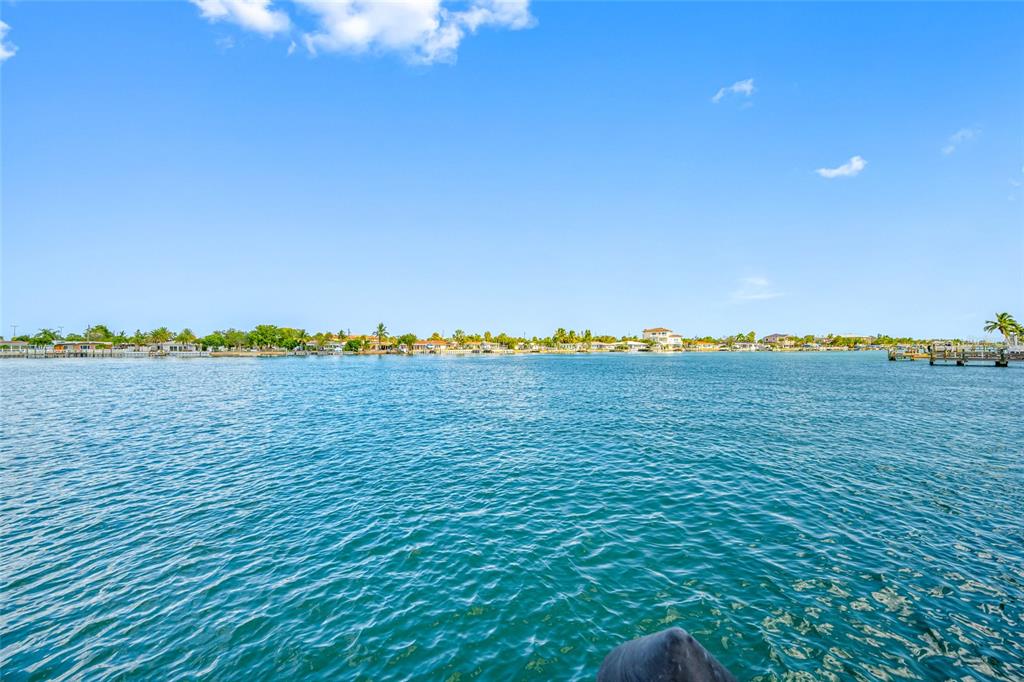 A view of a calm, blue waterway with a distant shoreline of houses and trees — 8575 SUNSET COURT, TREASURE ISLAND, FL