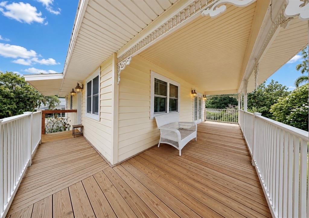 A wide wooden deck wraps around a yellow house with white railings and a bench — 8017 MAYS AVENUE, RIVERVIEW, FL