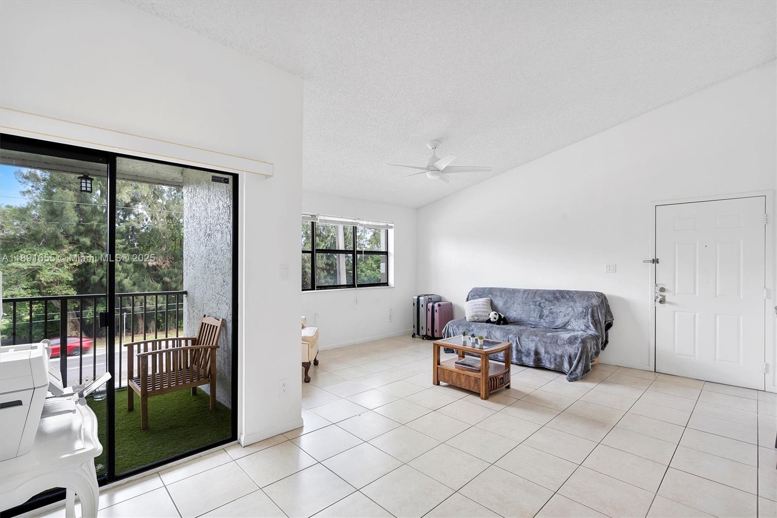 A living room features white walls, tile flooring, a sliding glass door, and a balcony — 610 S Park Rd # 1, Hollywood FL 33021, HOLLYWOOD, FL